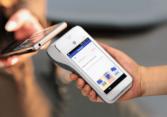 A customer paying by phone on a handheld card terminal